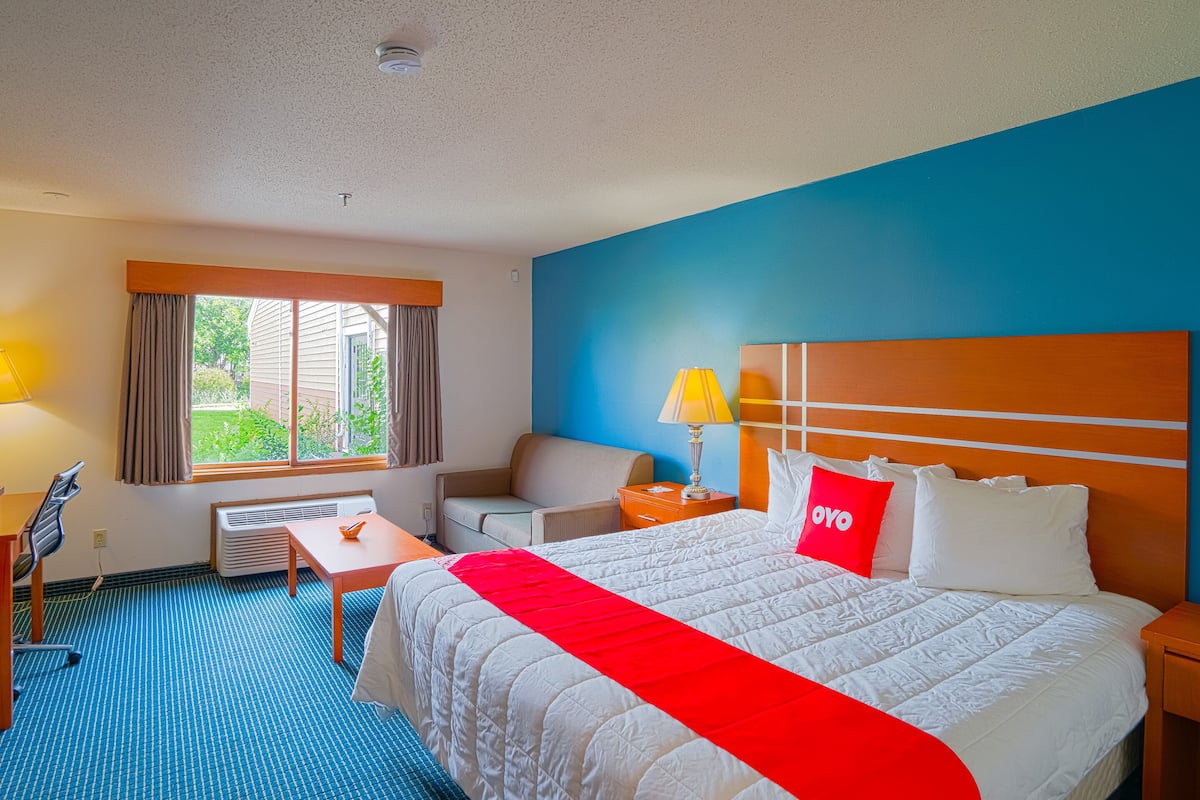 Une chambre d’hôtel avec un grand lit, un bureau, une chaise et une fenêtre avec des rideaux.