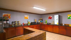 A kitchen area with wooden cabinets, a coffee machine, and various food items on the counter. - OYO Hotel Redwood Falls near Jackpot Casino (Redwood Falls)