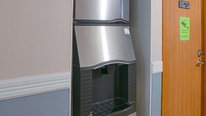 A kitchenette with a stainless steel refrigerator, a microwave, and a sink with a faucet. There is a sign on the door indicating 24-hour video surveillance and no trespassing. - OYO Hotel Redwood Falls near Jackpot Casino (Redwood Falls)