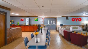 A hotel lobby with a long reception desk, a dining area with tables and chairs, and a seating area with sofas and armchairs. - OYO Hotel Redwood Falls near Jackpot Casino (Redwood Falls)