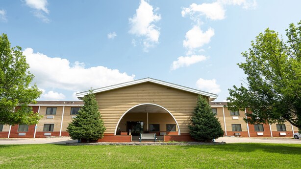 A building with a large arched entrance, a covered porch, and a lawn in front. - OYO Hotel Redwood Falls near Jackpot Casino (Redwood Falls)