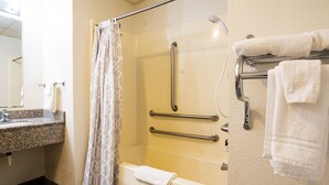 A bathroom with a shower, grab bars, a towel rack, and a sink. - OYO Hotel Redwood Falls near Jackpot Casino (Redwood Falls)