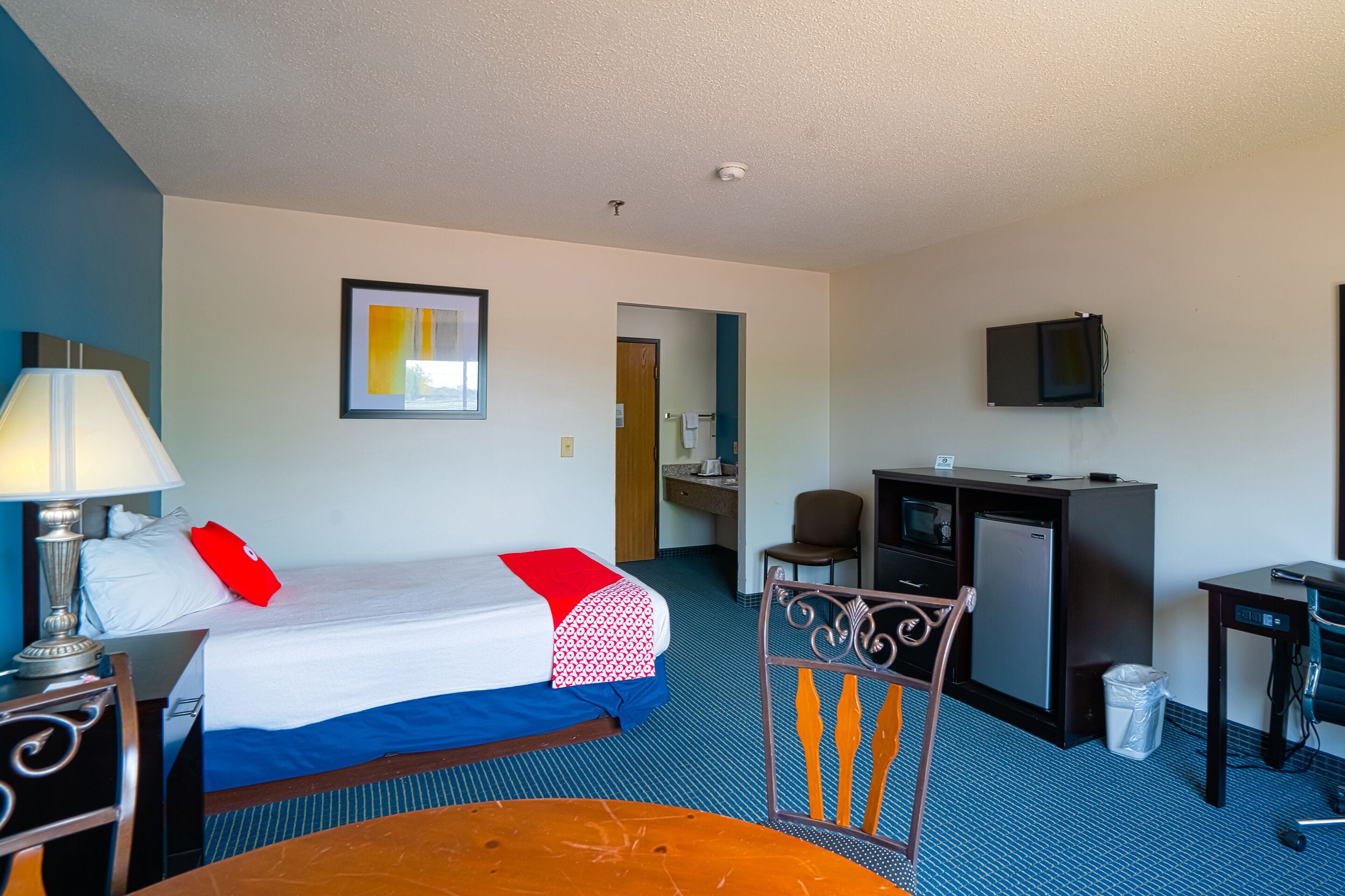 Ein Hotelzimmer mit Bett, Schreibtisch, Stuhl und einer kleinen Küchenzeile.