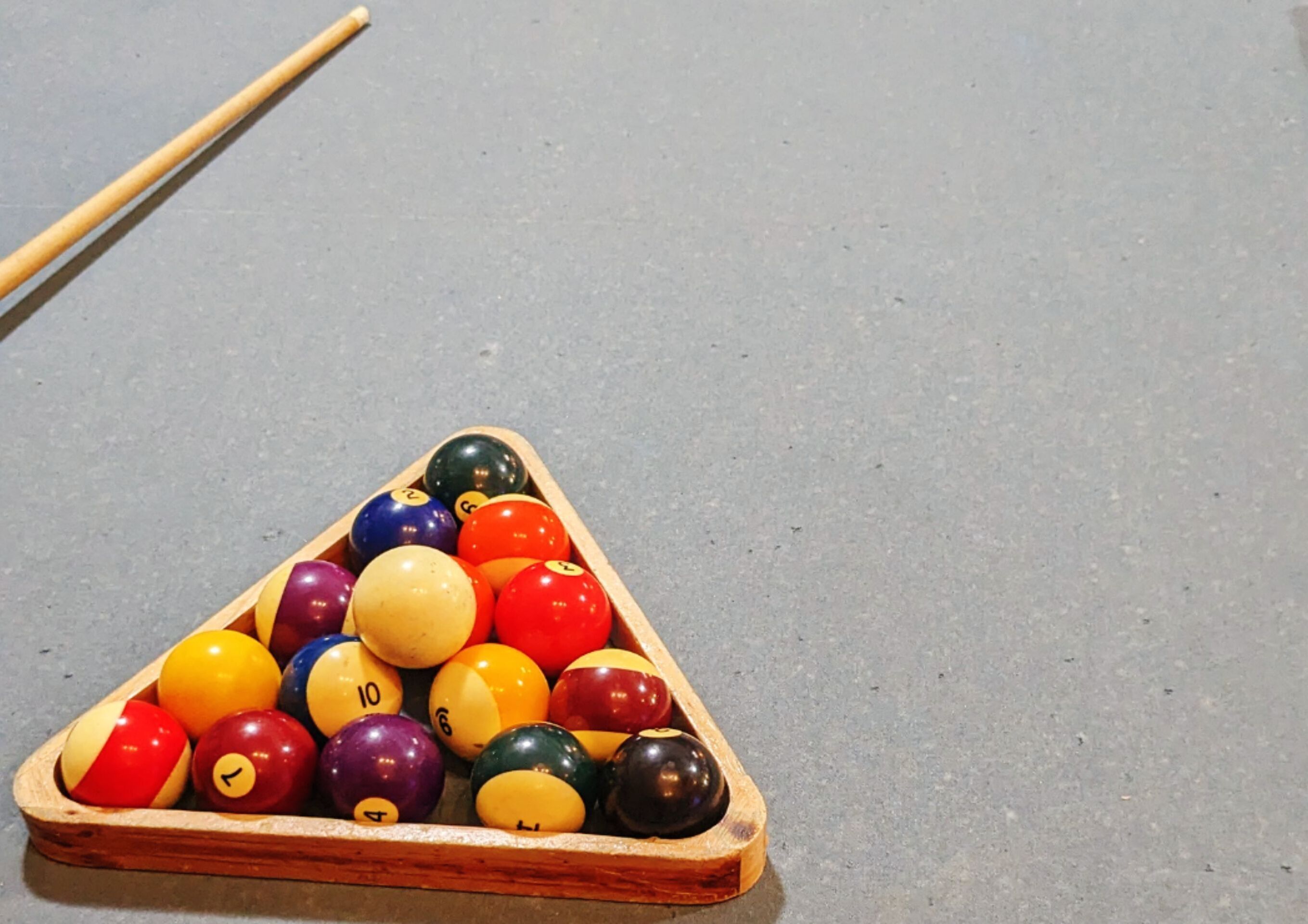 A pool table with a wooden triangle and various colored billiard balls.