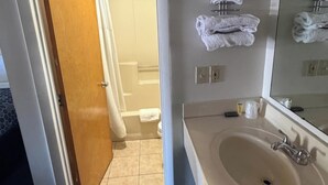 A bathroom with a sink, mirror, towels, and a shower area. - Relax Inn Dover Near Speedway (Dover)