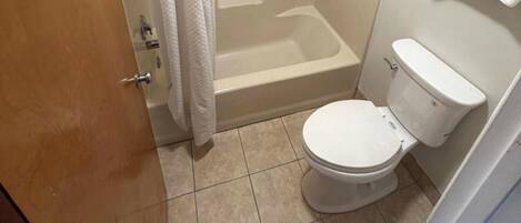 A bathroom with a toilet, bathtub, and shower curtain.