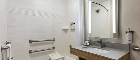 Un baño moderno con una bañera, un tocador con lavamanos, un espejo y una cortina de ducha.