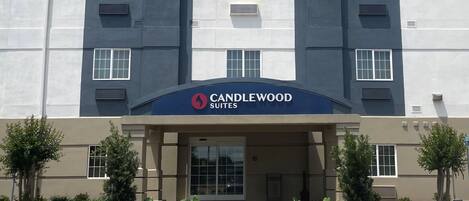 A modern hotel entrance with a sign reading "CANDLEWOOD SUITES".