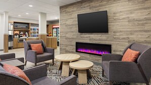 A modern lounge area with sofas, a flat-screen TV, and a fireplace. - Candlewood Suites Tuscaloosa by IHG (Tuscaloosa)