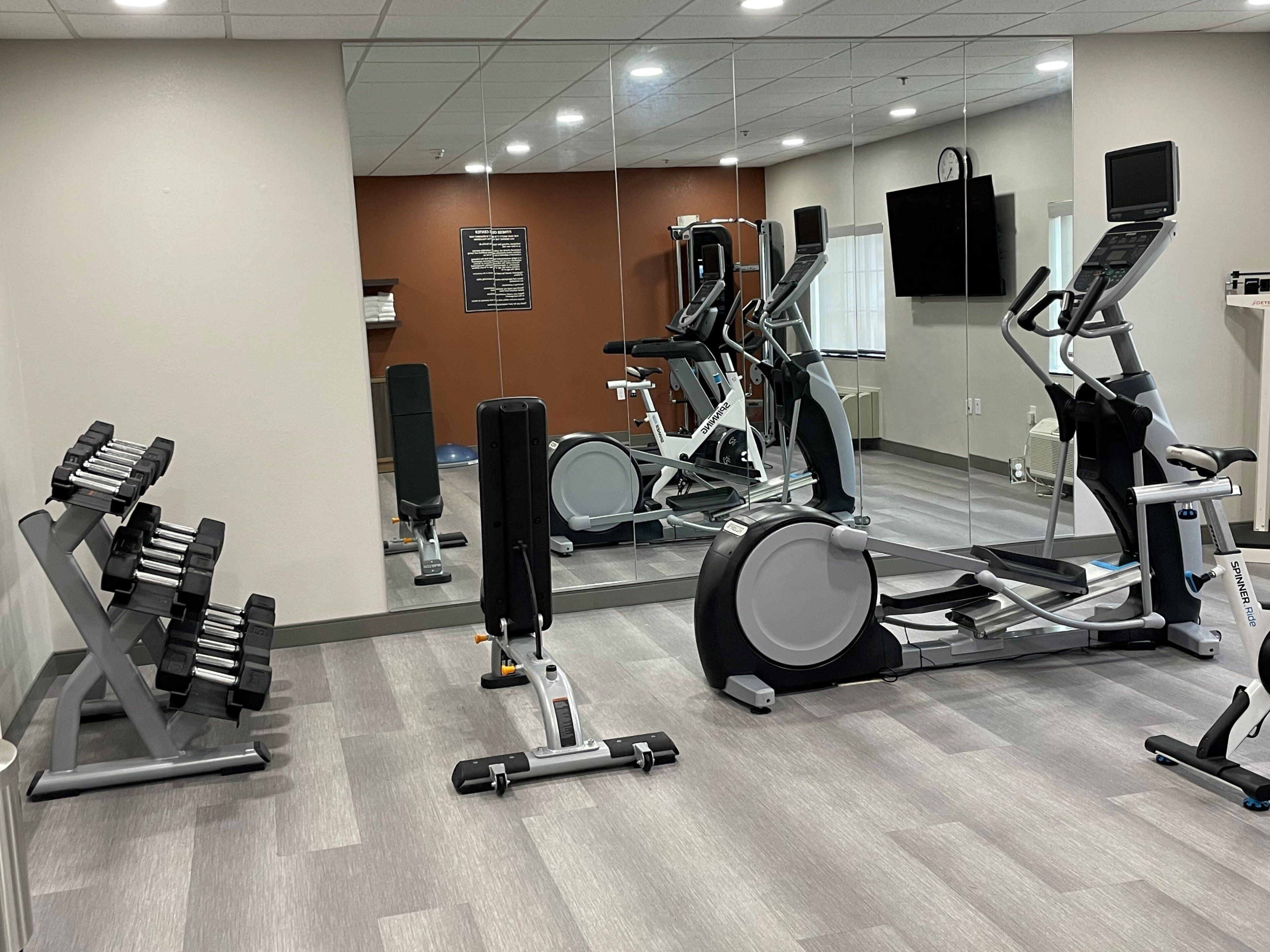 A gym with various exercise equipment including treadmills, stationary bikes, and weight machines.