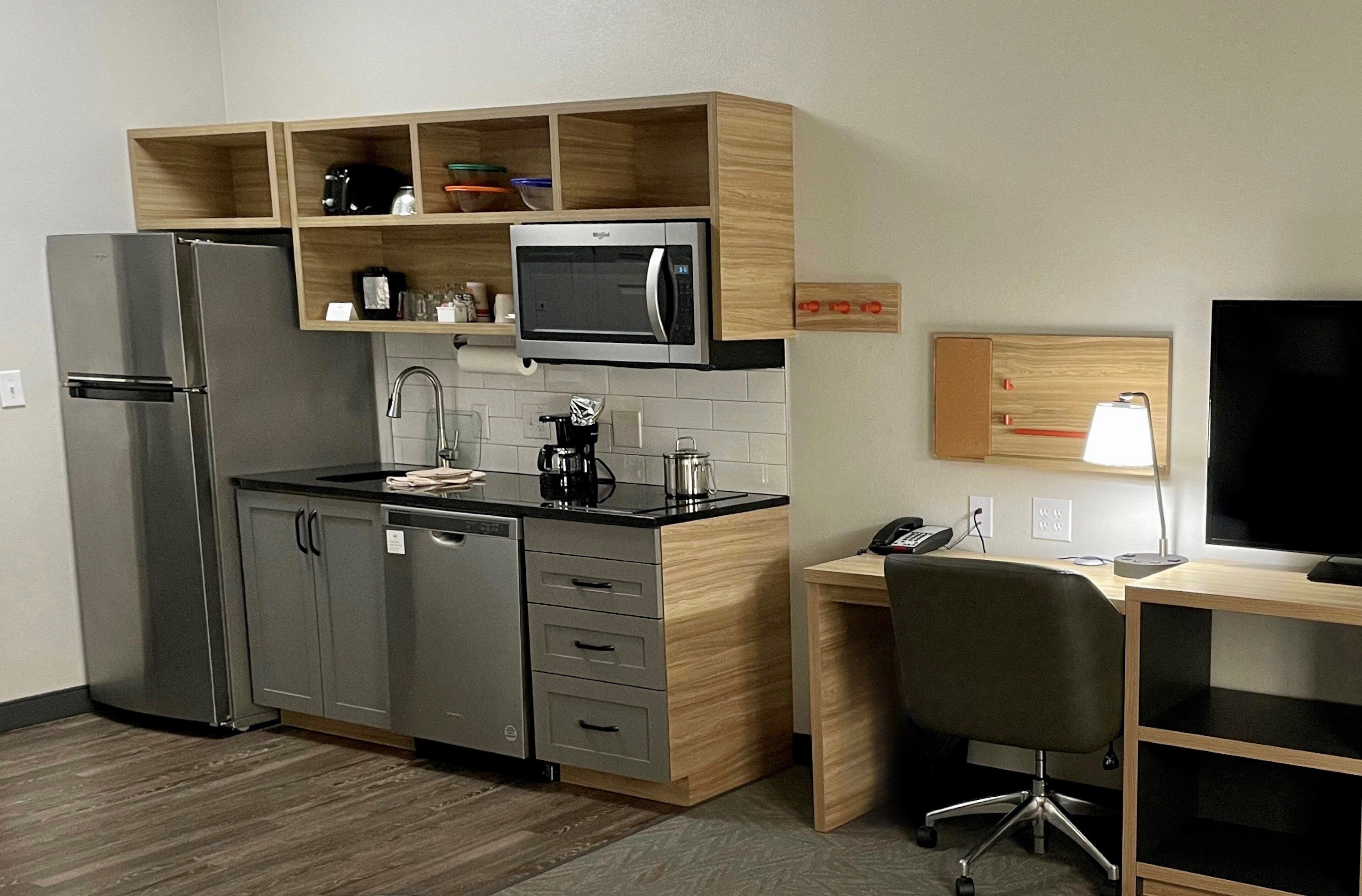 Cocina compacta con refrigerador, microondas y cafetera.
