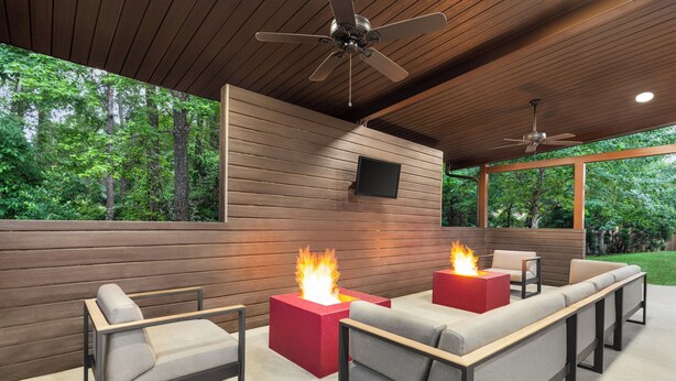 An outdoor seating area with fire pits, wooden panel walls, ceiling fans, and a TV mounted on the wall. - Candlewood Suites Tuscaloosa by IHG (Tuscaloosa)