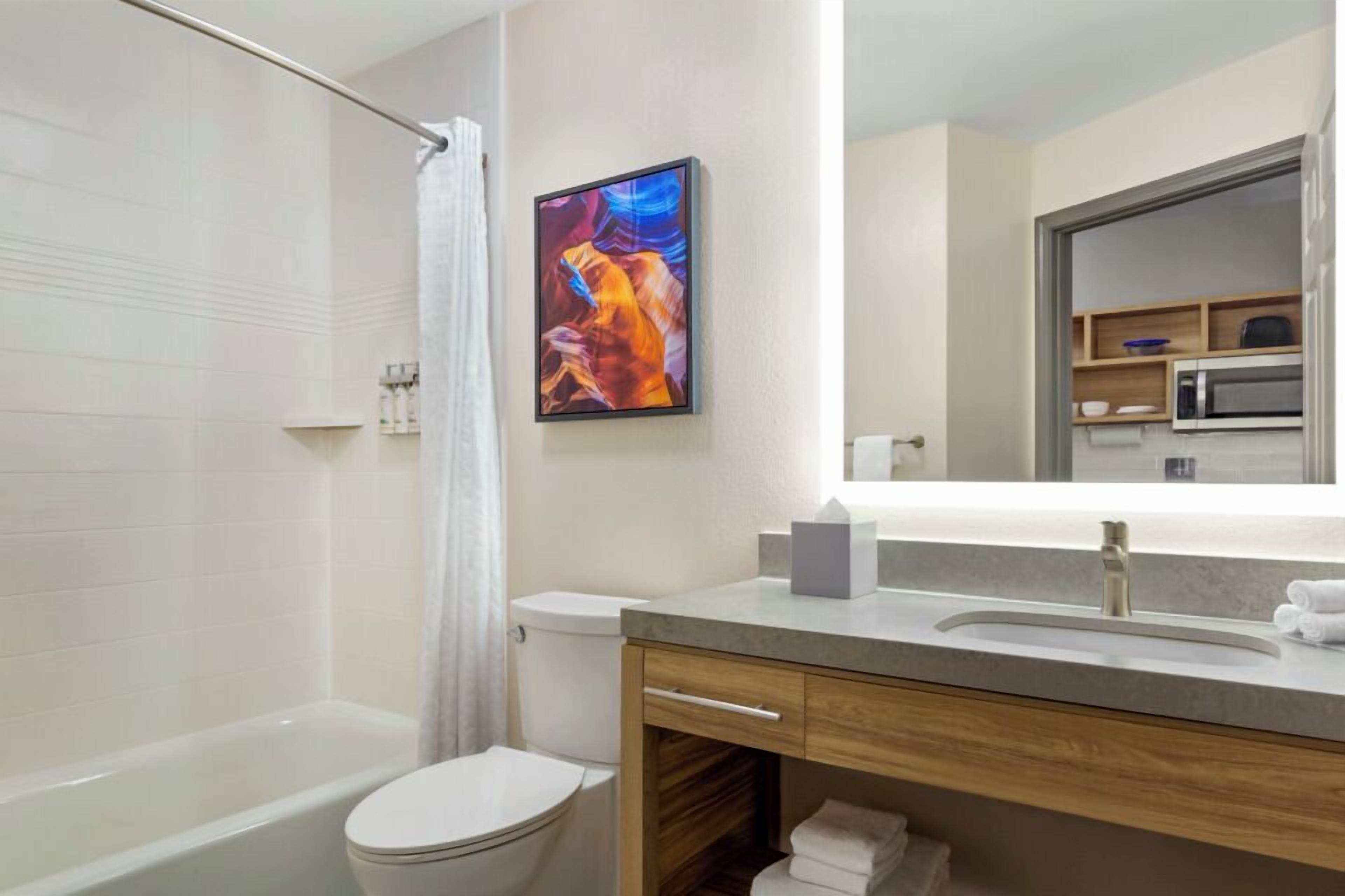 A modern bathroom with a bathtub, toilet, and a vanity with a sink and mirror.