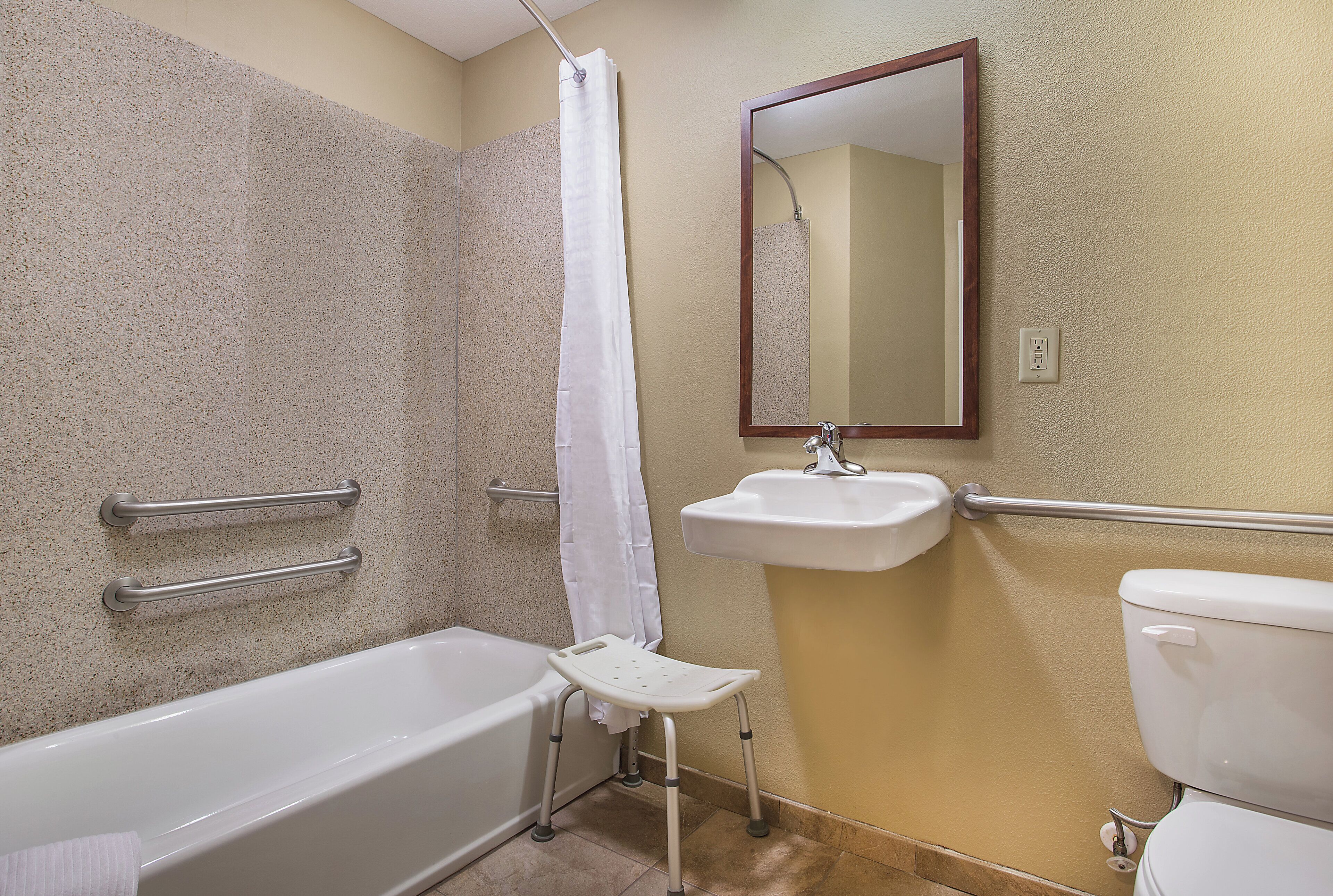 A bathroom with a bathtub, a sink, a toilet, a shower curtain, and a mirror.
