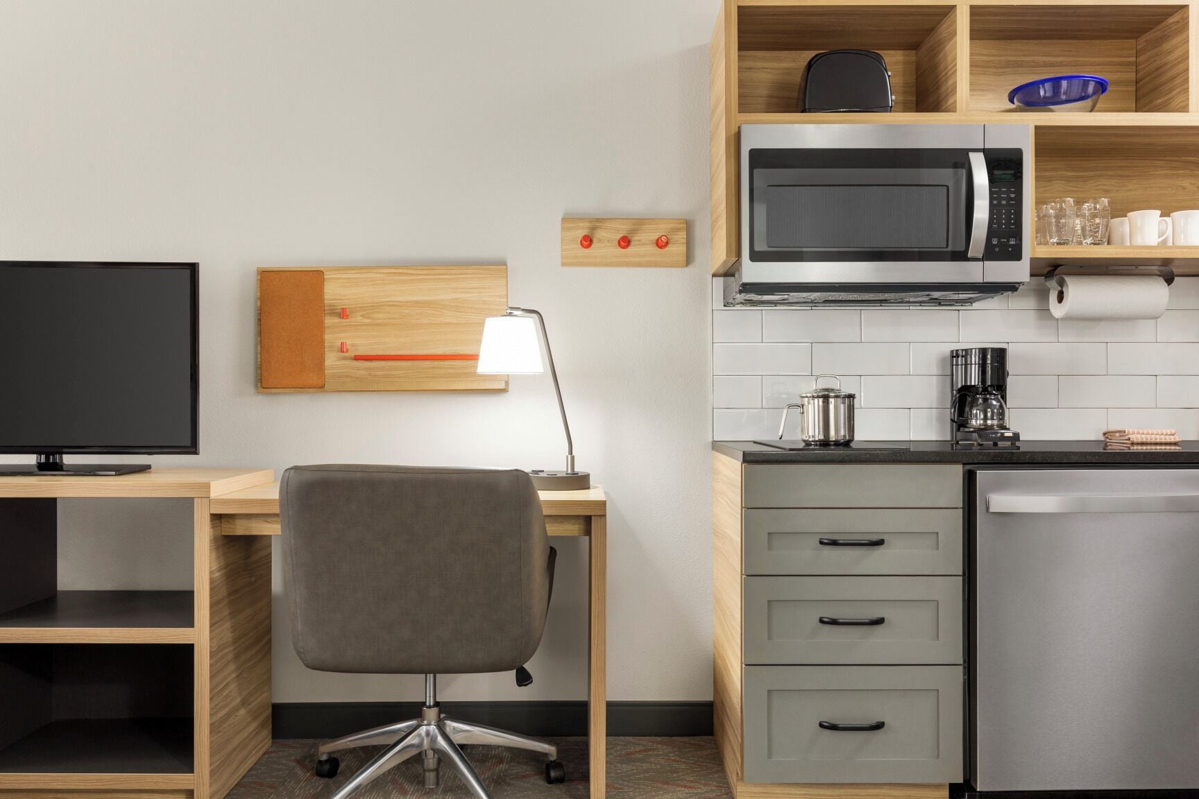 A modern kitchen with a microwave, coffee maker, and a small cabinet.