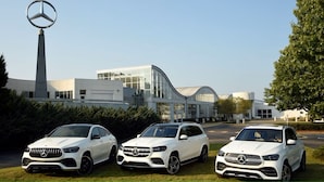 Three white Mercedes-Benz cars parked in front of a modern building with a tall tower and curved glass facade. - Candlewood Suites Tuscaloosa by IHG (Tuscaloosa)