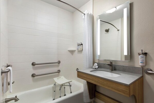 A bathroom with a bathtub, a sink, a mirror, and a shower curtain.