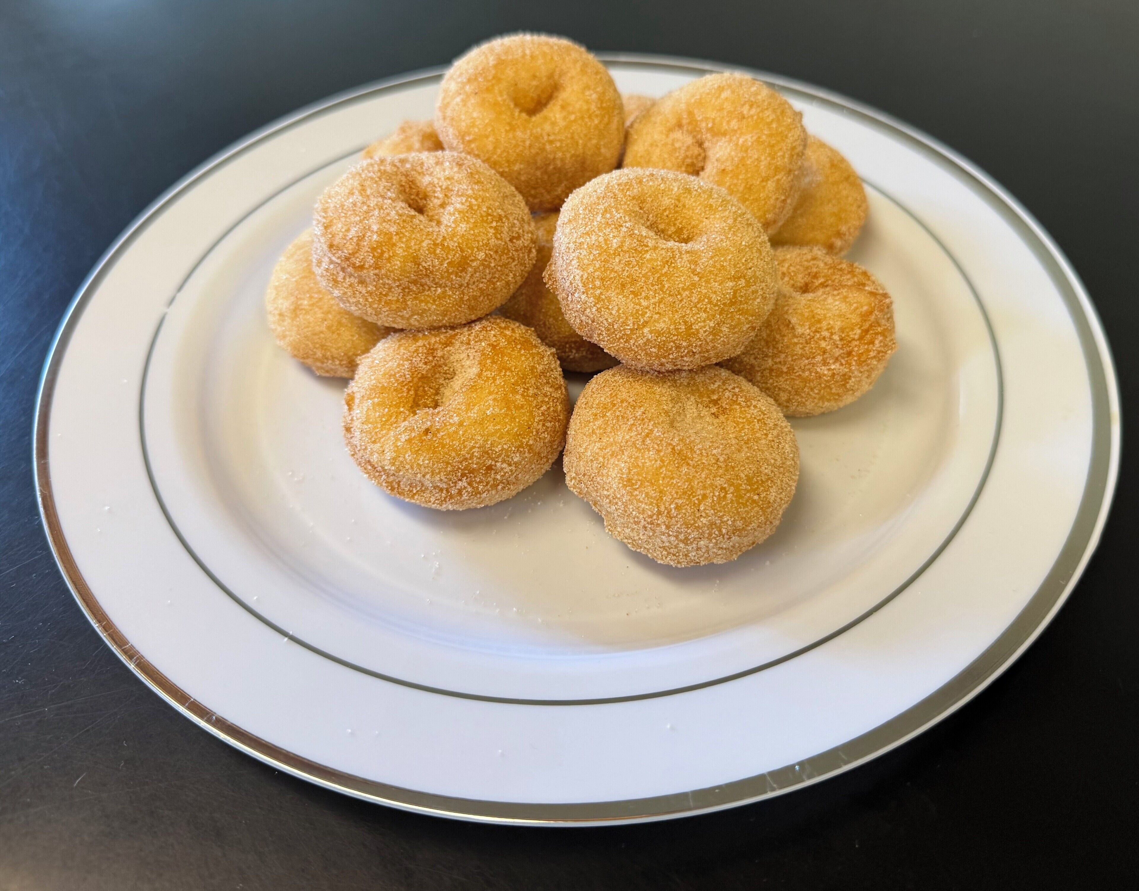 A plate of round, sugar-coated doughnuts.