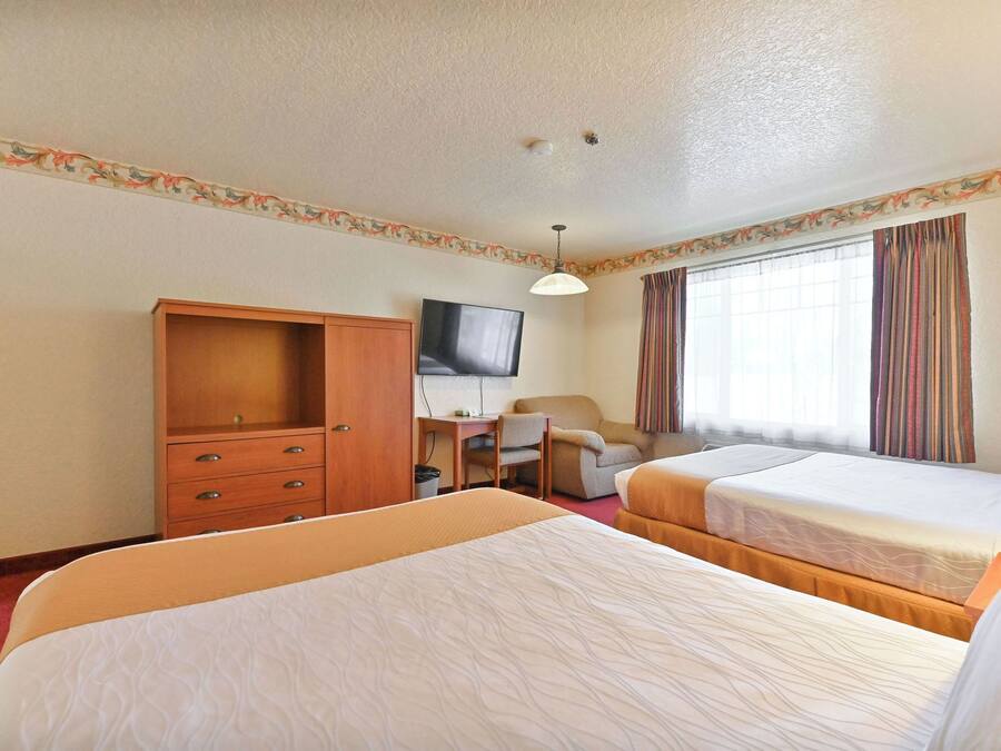 Habitación de hotel con dos camas, un escritorio, televisor y armario.