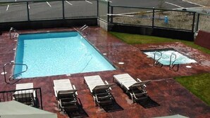 A rectangular pool with a diving board and a set of sun loungers.