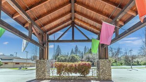 A covered outdoor area with a stone wall, wooden beams, and flags.