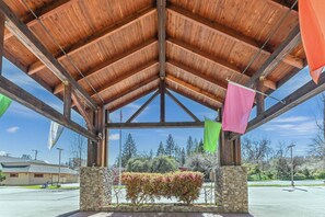 A covered outdoor area with a stone wall, wooden beams, and flags.