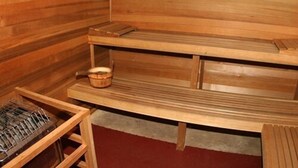 A wooden sauna with a bench, a shelf with a basket, and a sauna heater.