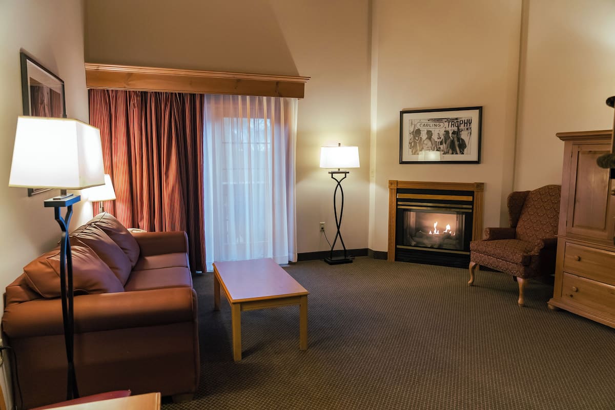 Une chambre d’hôtel avec un canapé, une table, une lampe, une cheminée et une chaise.