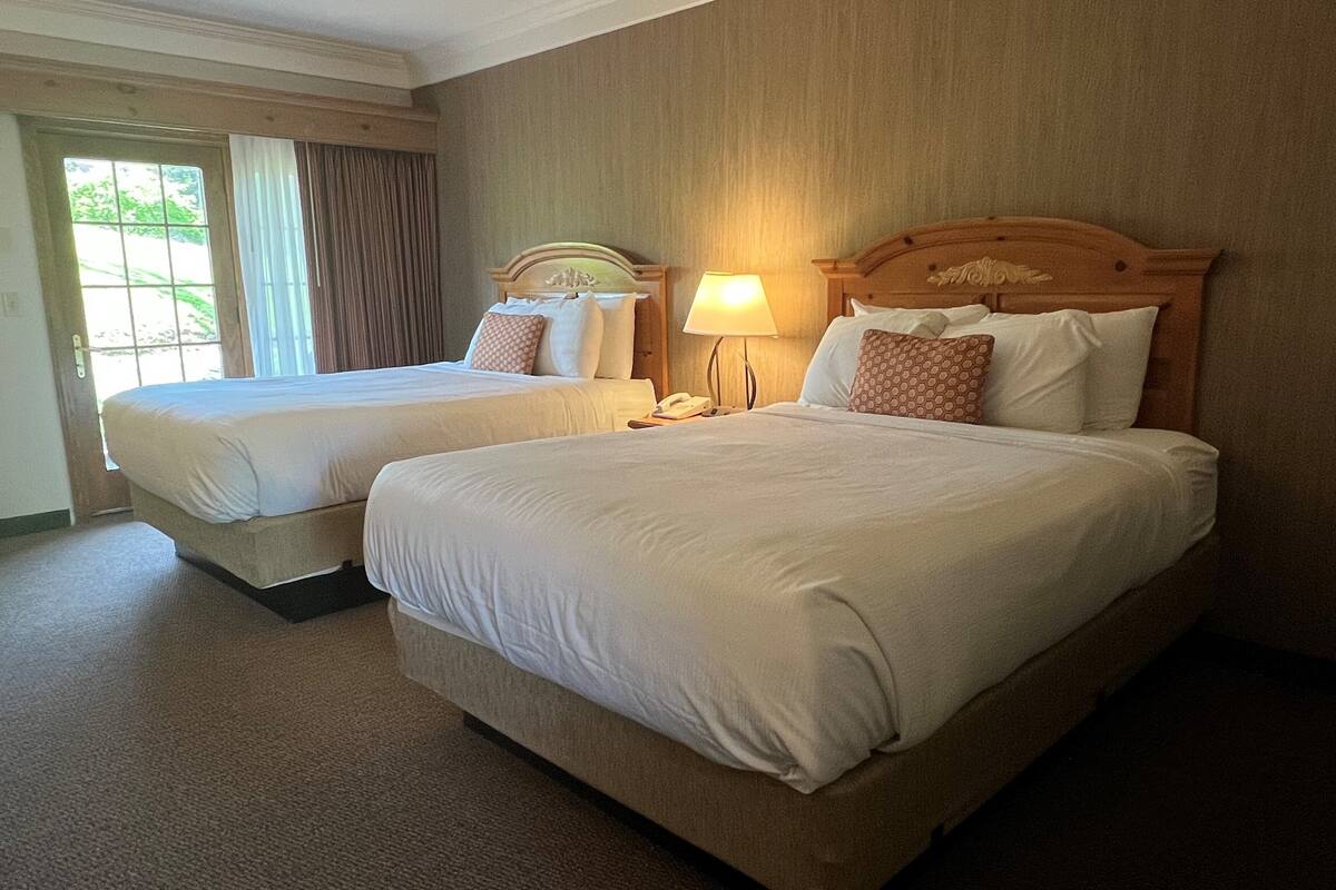 Une chambre d’hôtel avec deux lits, un téléphone et une lampe.