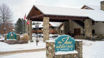 A hotel entrance with a stone sign, American flag, and a covered area with stone pillars.