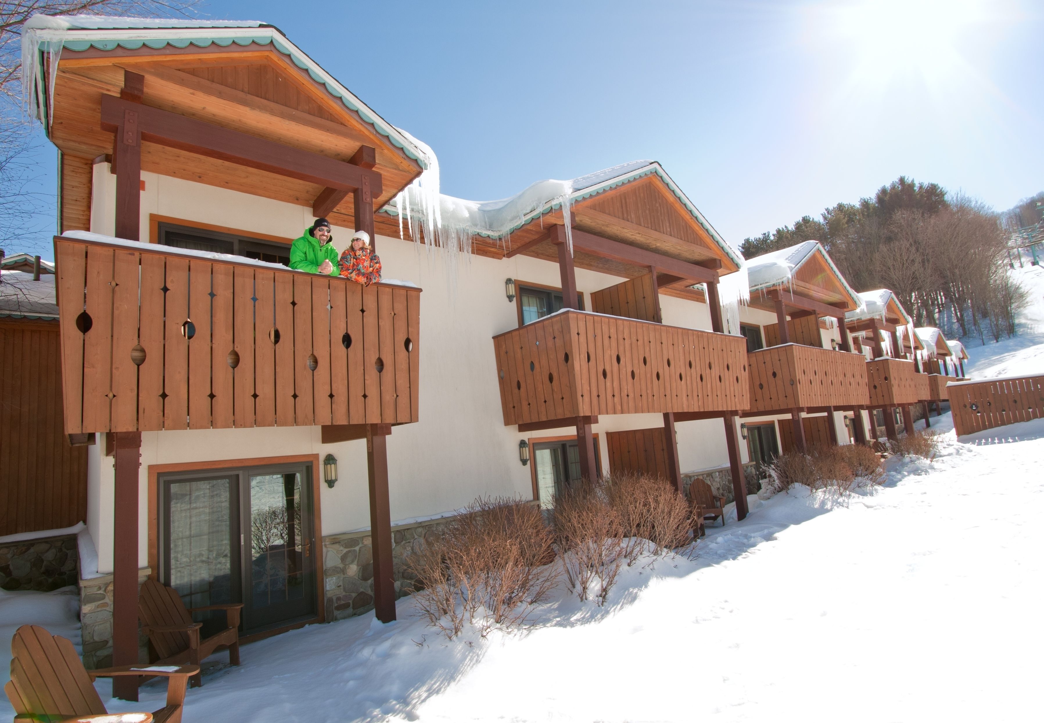 Una hilera de cabañas de madera con balcones, cada una con base de piedra y estructura superior de madera.