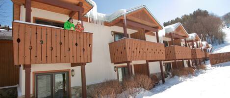 Una hilera de cabañas de madera con balcones, cada una con base de piedra y estructura superior de madera.