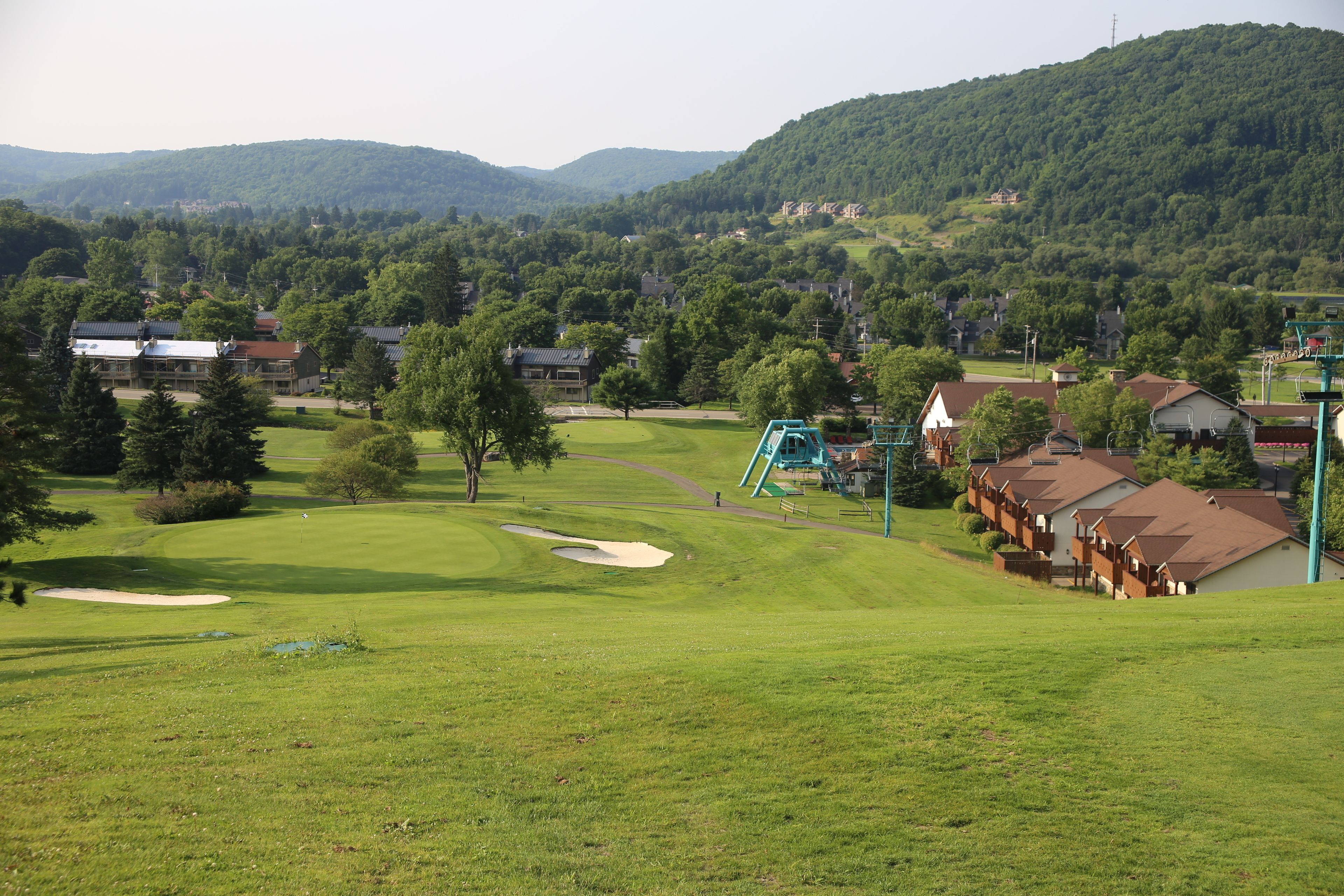 A golf course with a clubhouse, a playground, and residential buildings in the background.
