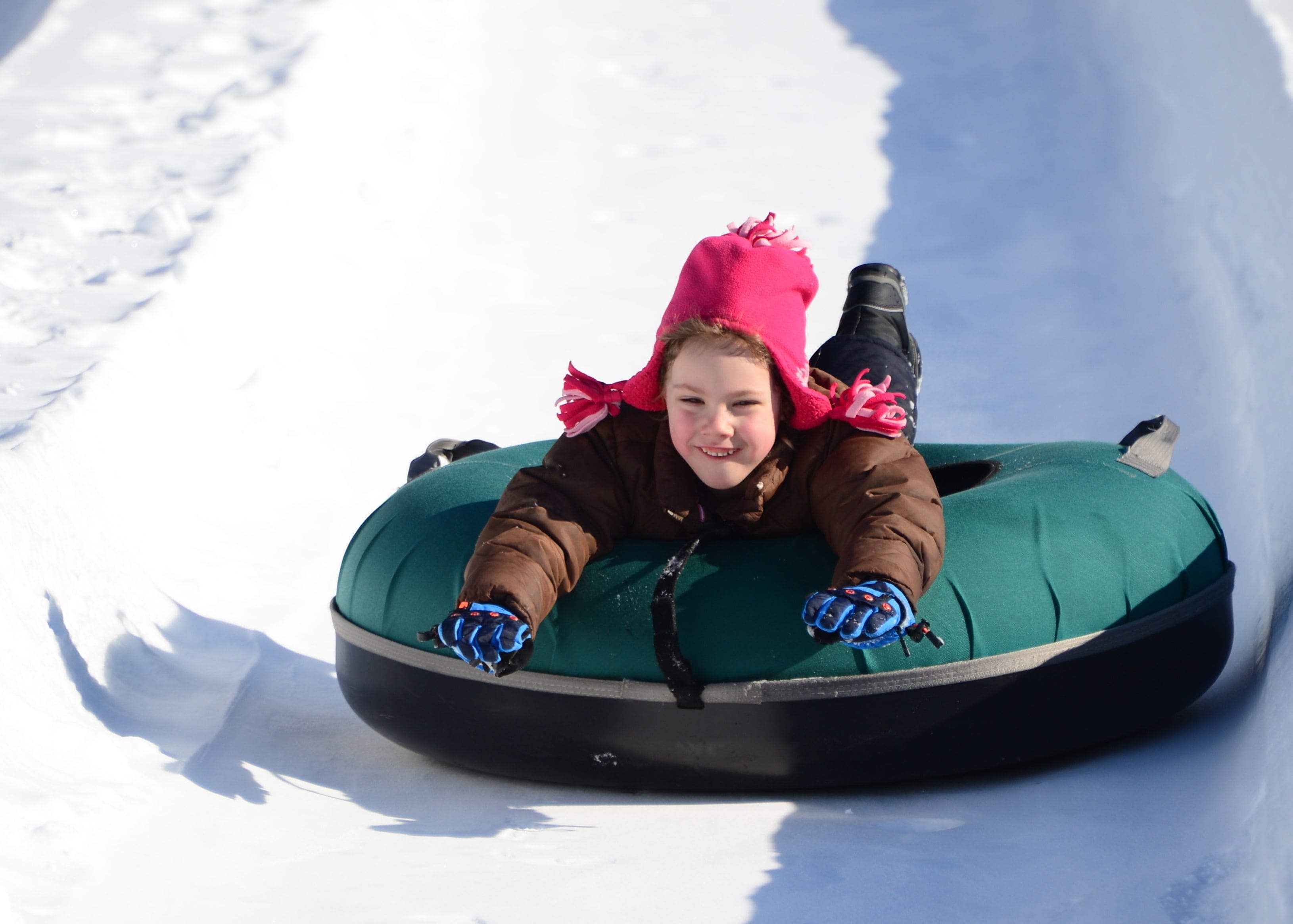 Una persona acostada en un flotador para nieve sobre una pendiente nevada.