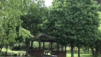 En park med en pavillon, borde til picnic og en sti.