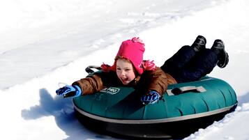 Une personne allongée sur une bouée à neige dans un environnement enneigé.