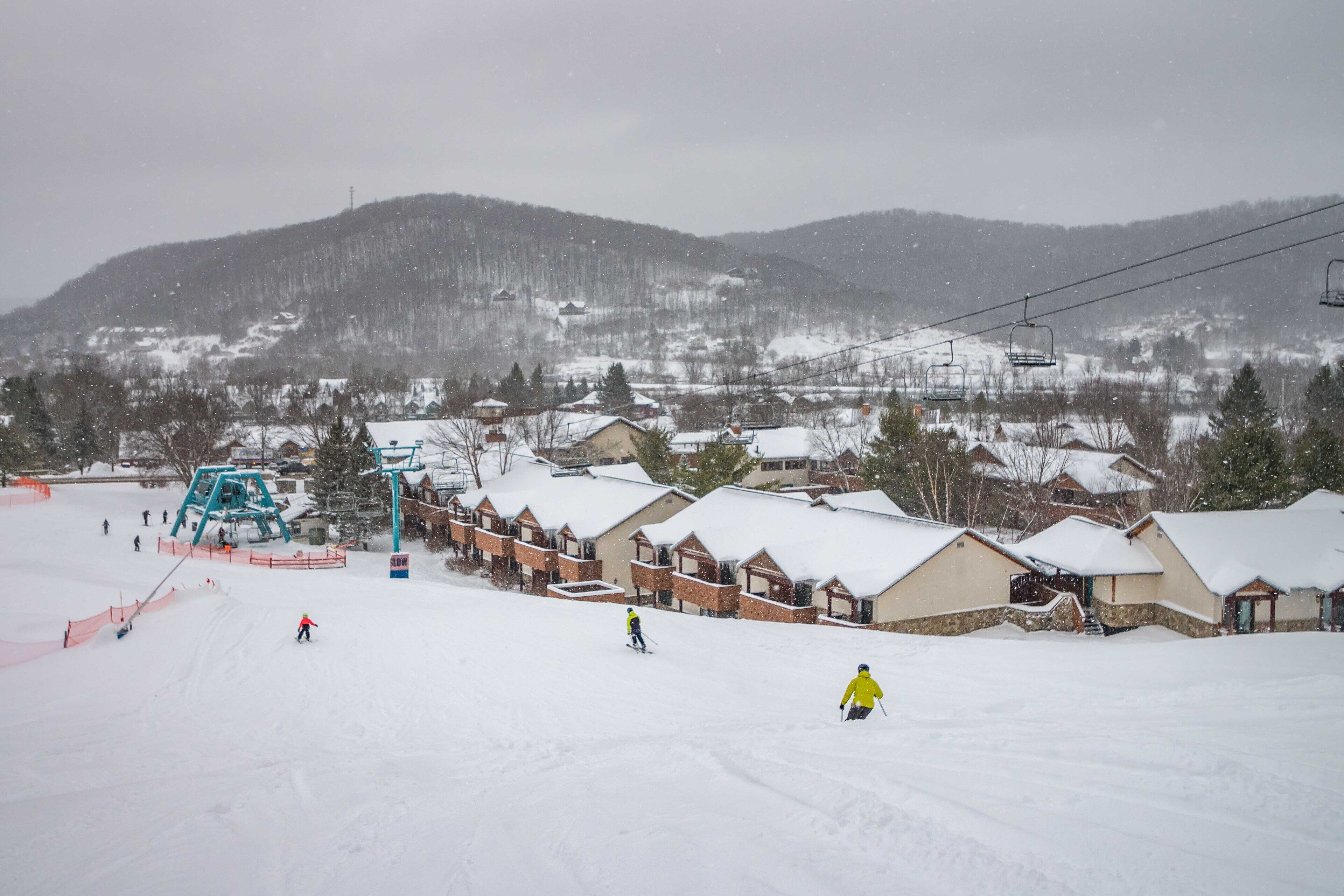 Une station de ski avec des bâtiments recouverts de neige et un télésiège en arrière-plan.