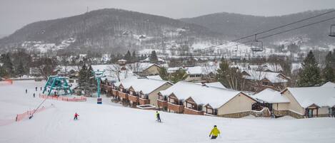Une station de ski avec des bâtiments recouverts de neige et un télésiège en arrière-plan.