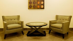 Two armchairs facing each other with a round table in between, set against a plain wall with a geometric artwork above. - Holiday Inn Express & Suites Borger by IHG (Borger)