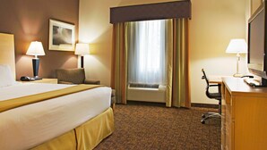 A hotel room with a large bed, a desk, a chair, a desk lamp, a television, and a window with curtains. - Holiday Inn Express & Suites Borger by IHG (Borger)