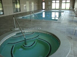 Una piscina interior con agua cristalina, líneas de profundidad marcadas y un puesto de socorrista.