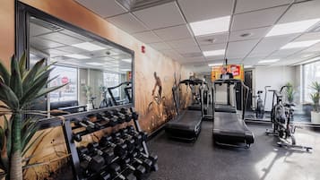 Un gimnasio con cintas de correr, mancuernas y bicicletas estáticas.