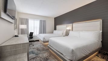 A hotel room with two beds, a desk, a chair, and a TV.