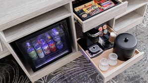 A minibar with snacks, a beverage cooler, and a tray with cups and a coffee maker. - Oakfield Hotel & Suites, Ascend Collection, Rochester-Pittsford NY (Rochester)