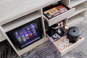 A minibar with snacks, a beverage cooler, and a tray with cups and a coffee maker. - Oakfield Hotel & Suites, Ascend Collection, Rochester-Pittsford NY (Rochester)