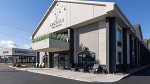 A hotel with a modern design, a covered entrance, and outdoor seating. - Oakfield Hotel & Suites, Ascend Collection, Rochester-Pittsford NY (Rochester)