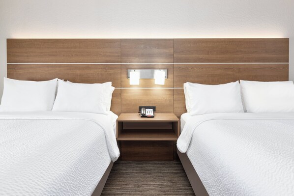 A hotel room with two beds, a wooden headboard, a bedside table with a phone, and a wall-mounted light fixture. - Holiday Inn Express Amarillo South by IHG (Amarillo)