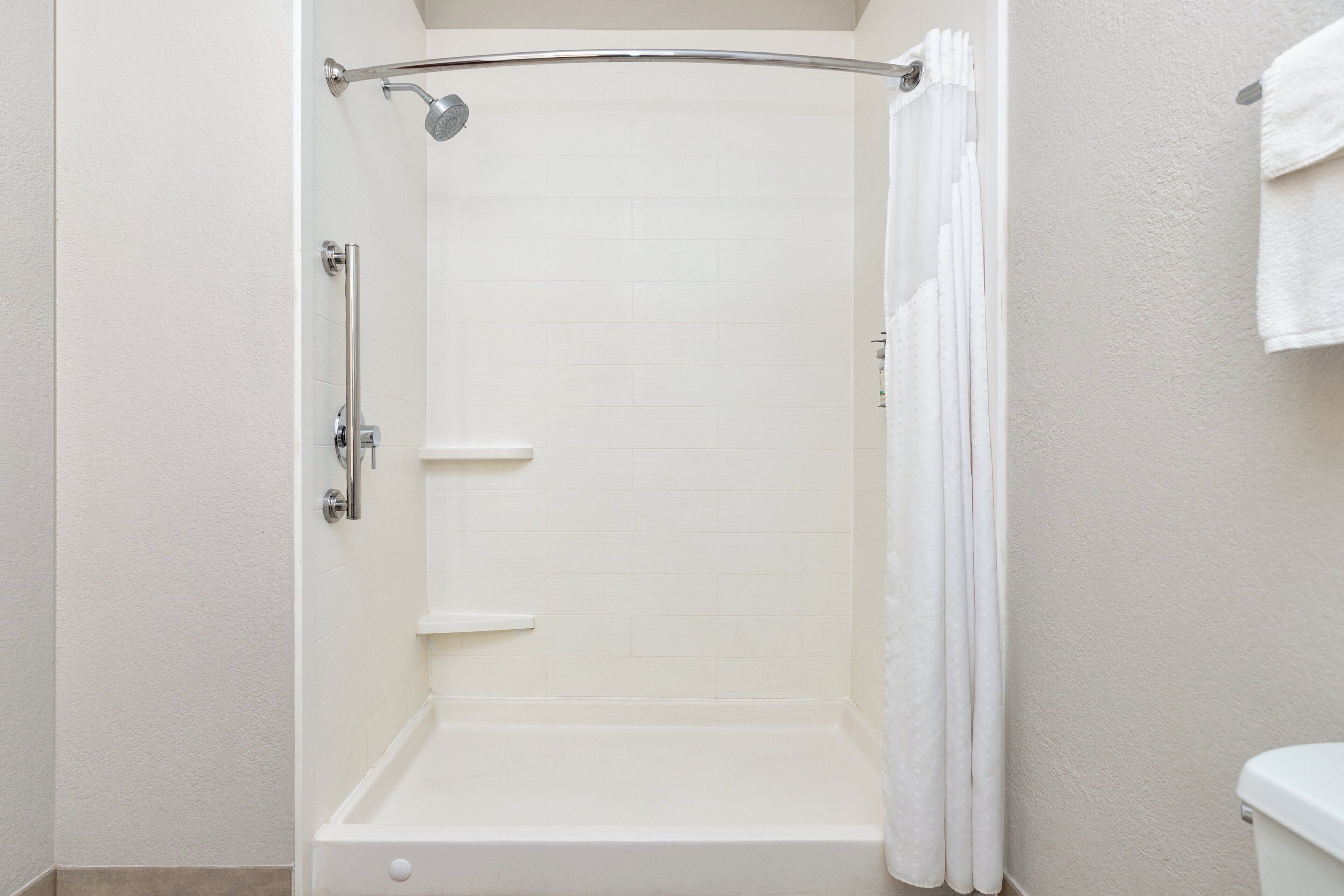 A walk-in shower with a glass door, a showerhead, and a towel rack.