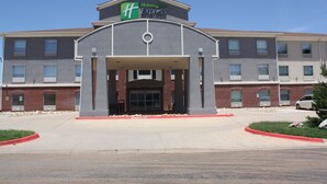 A Holiday Inn Express building with a brick facade, large windows, and a covered entrance. - Holiday Inn Express Hotel & Suites Shamrock North by IHG (Shamrock)