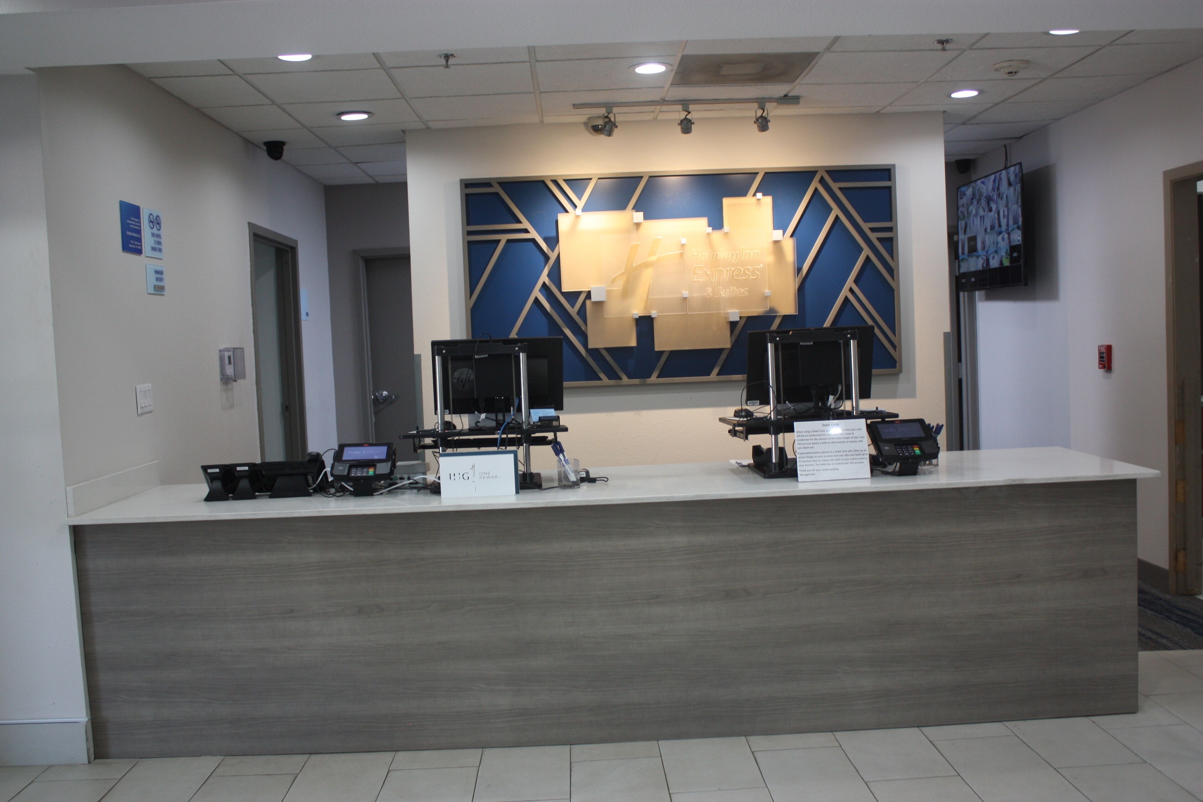 A reception desk with two computer monitors, a cash register, and a telephone.